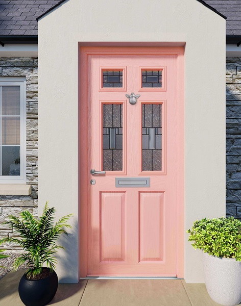 A light pink composite door with four decorative glass panels, accompanied by two potted plants on either side.