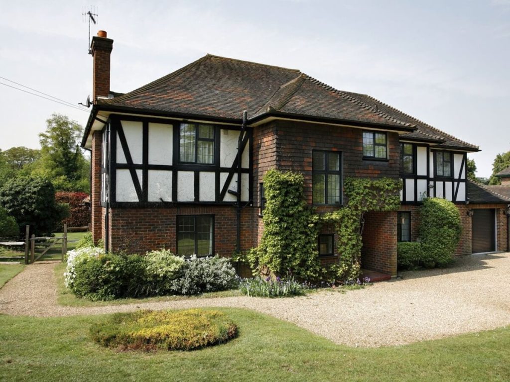 Smart Alitherm 800 windows on a traditional Tudor-style home with brick and timber accents and lush greenery.